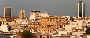 A skyline in Tunisia shows brick and concrete buildings haphazardly built in a jumble, and one or two palm trees.