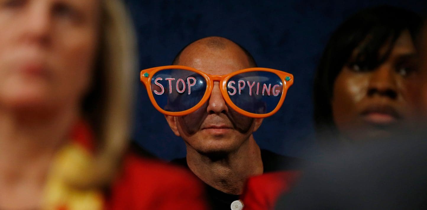 A man wearing oversized sunglasses with 'Stop Spying' written on them.