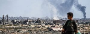 boy standing in front of destroyed Gaza City