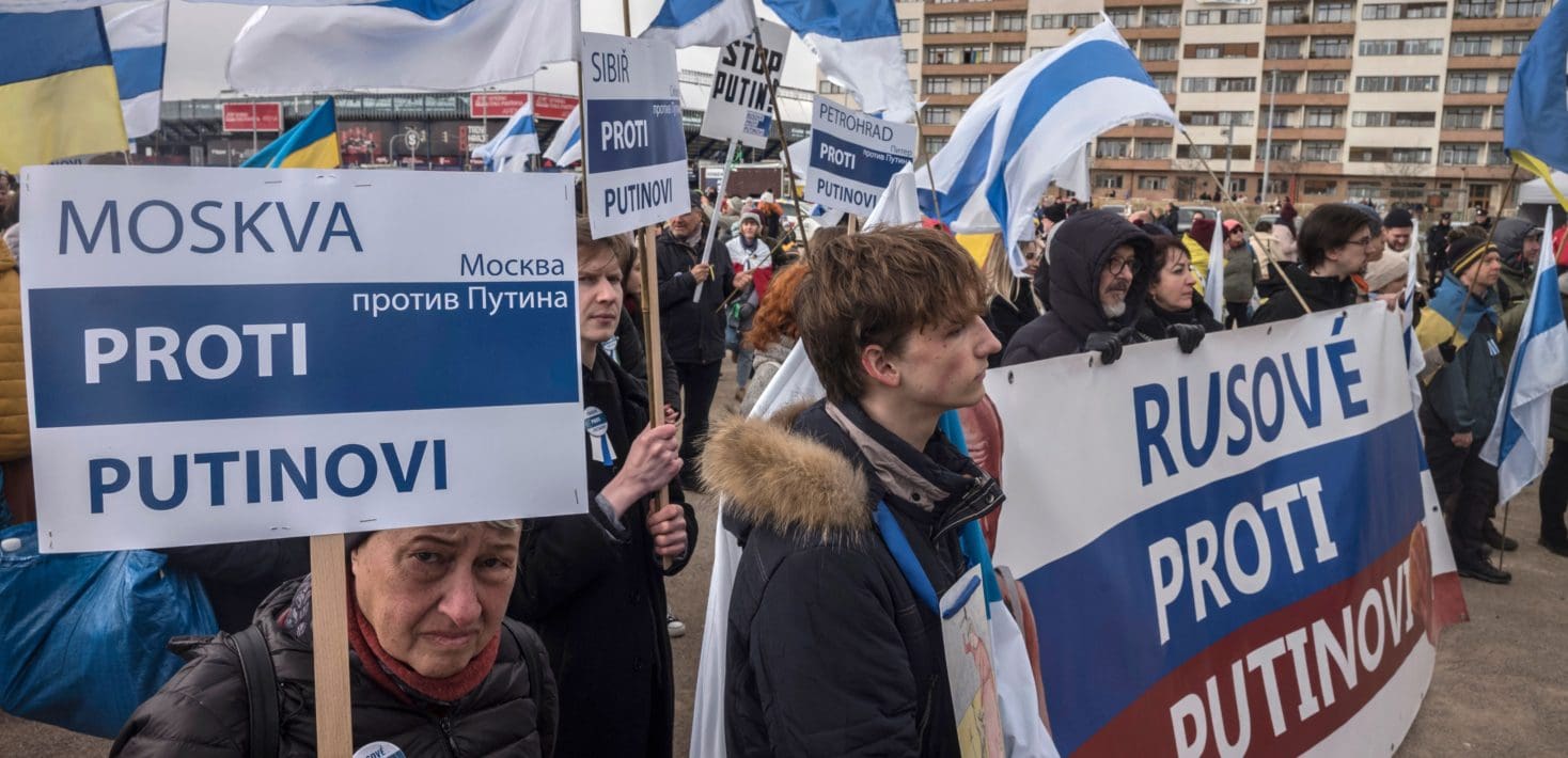 A group of people holding up a banner and signs at a protest in Russia.