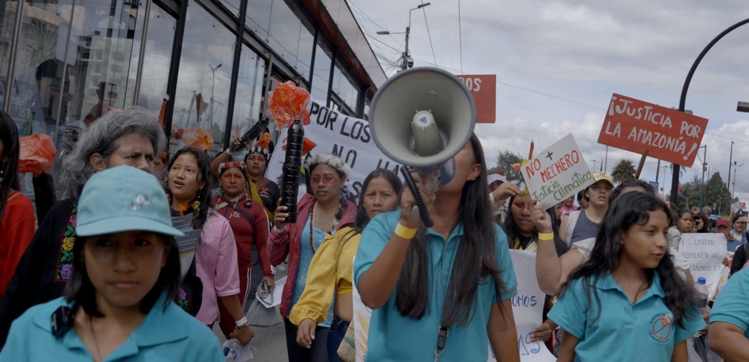 Women marching in protest with signs and megaphone.