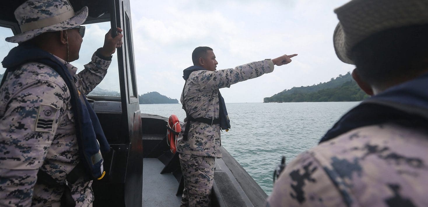 man in camouflage on a boat pointing