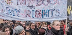 Dozens of people at a protest, holding the banner 'My Body My Rights'