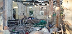 Rubble and charred hospital beds under a destroyed roof.