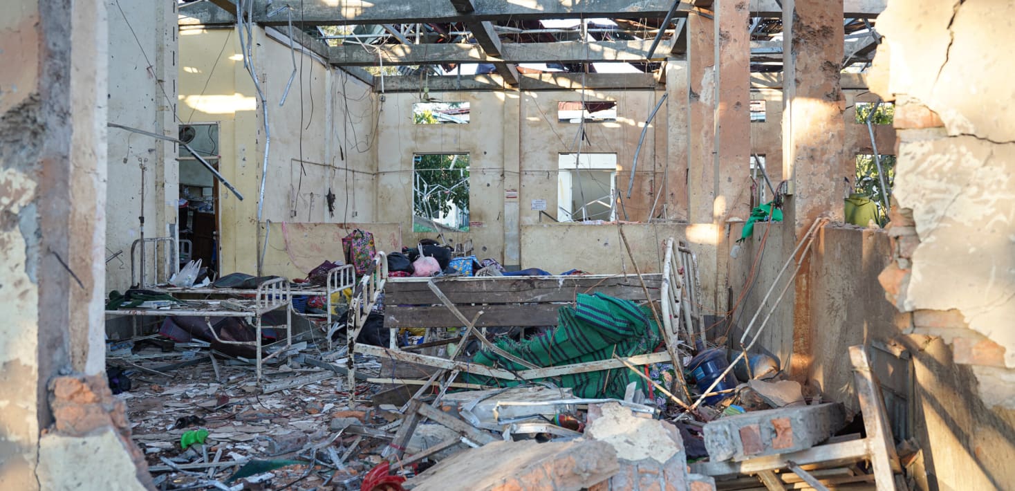 Rubble and charred hospital beds under a destroyed roof.
