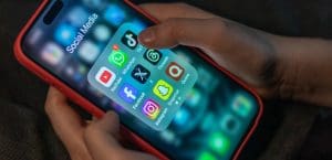 Hands holding a phone with the logos of social media companies.