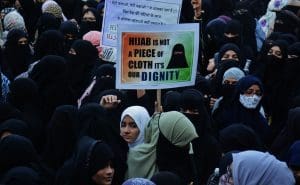 A group of women in hijabs holding up signs, one of which reads, 