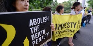 People hold black and yellow signs and banners that say 