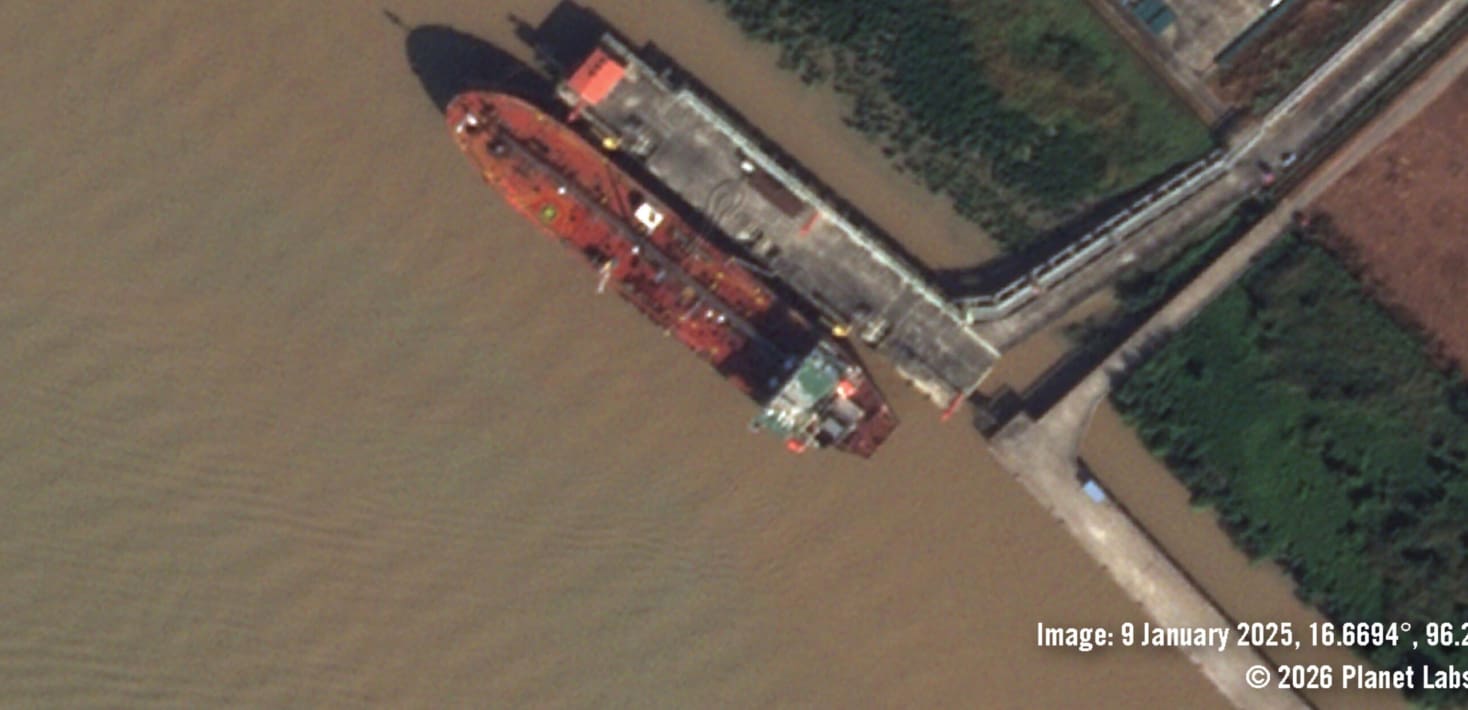 a satellite image of a large ship docked at a small concrete port in brown muddy water.