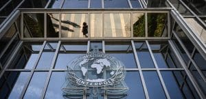 An exterior shot of the Interpol headquarters in Lyon. A glass building with a map of the world on the front exterior, while the text 