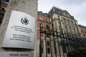 A plaque marks the office of the UN high commissioner for human rights, with a tall stately building behind it.