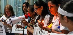 Women holding signs and a candle