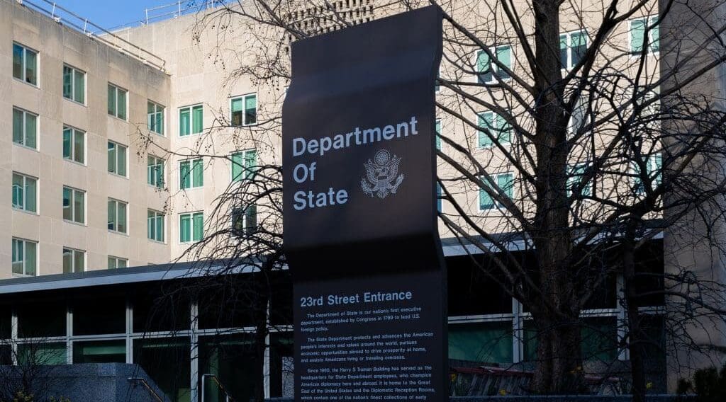 The exterior of the U.S. Department of State. A brown building with the sign 'Department of State.'