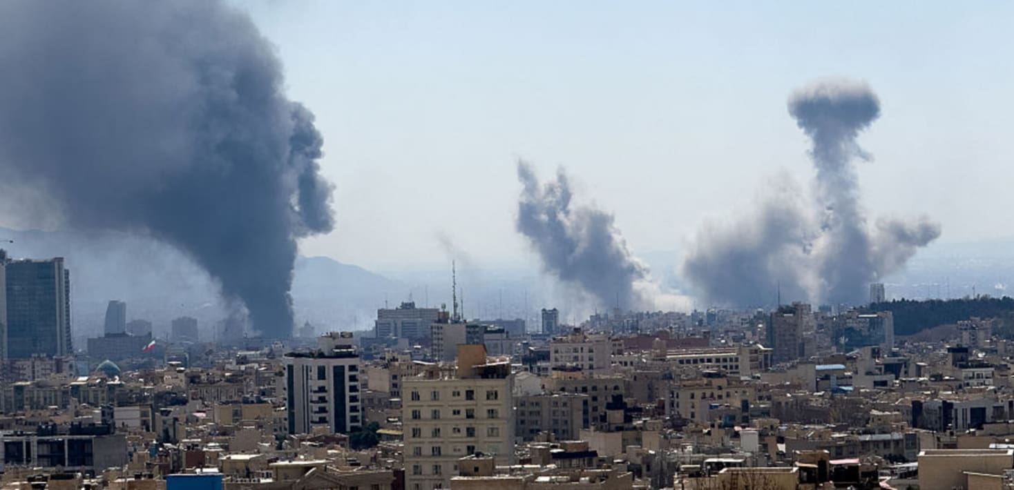a bombed city in Iran with smoke in multiple places coming from buildings