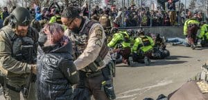 Woman getting handcuff with other people also being detained by police.