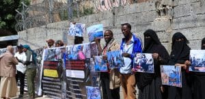 Protesters hold signs showing the carnage in the aftermath of the air strike on a migrant detention center in Yemen.