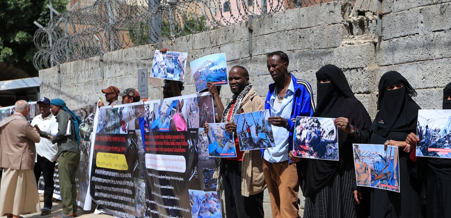 Protesters hold signs showing the carnage in the aftermath of the air strike on a migrant detention center in Yemen.