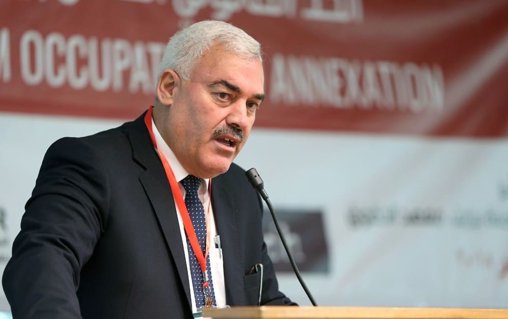 A middle-aged man speaking on a podium with a microphone.