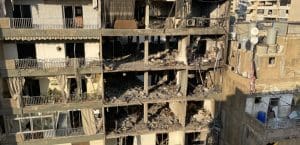 A hallowed out building from a bomb explosion, surrounded by rubble.