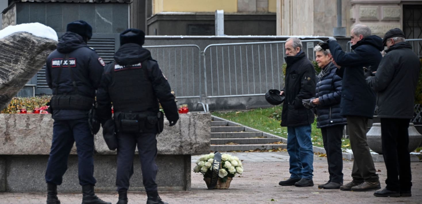 Four people laying flowers at a monument. Two police officers stand on the side.