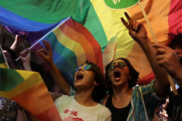 Two people cheering and holding LGBTQI flags