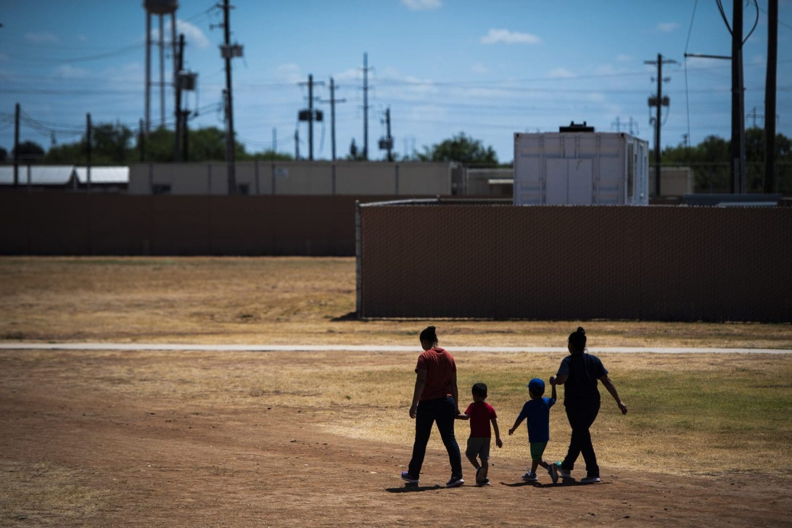 DILLEY, TX - AUGUST 23 : Immigrant woman and children walk across a field as U.S. Immigration and Customs Enforcement (ICE) and Enforcement and Removal Operations (ERO) hosts a media tour at the South Texas Family Residential Center, which houses families who are pending disposition of their immigration cases on Friday, Aug 23, 2019 in Dilley, TX.