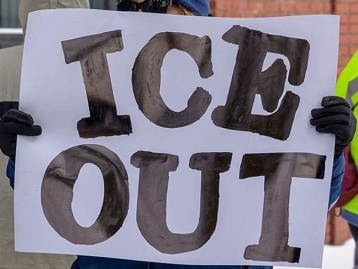 person holds ICE out sign