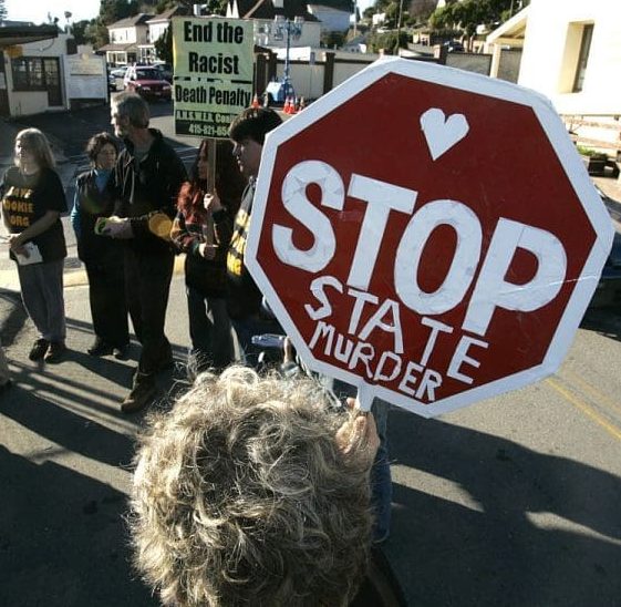 woman holds a Stop State Murder sign at a protest
