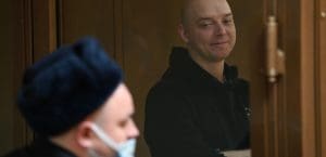 A young, White, bald male wearing a black hoodie and smiling.