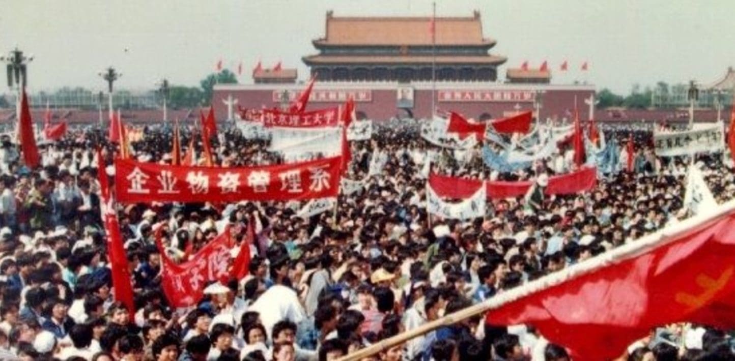 Masses of protesters in China holding red protest banners.