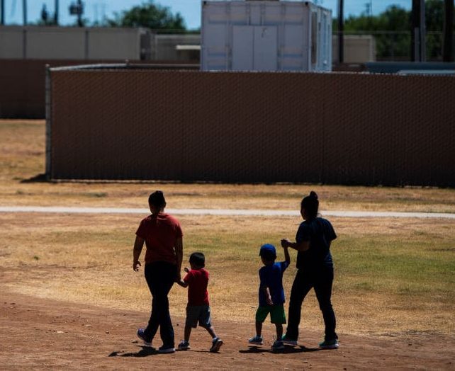 DILLEY, TX - AUGUST 23 : Immigrant woman and children walk across a field as U.S. Immigration and Customs Enforcement (ICE)