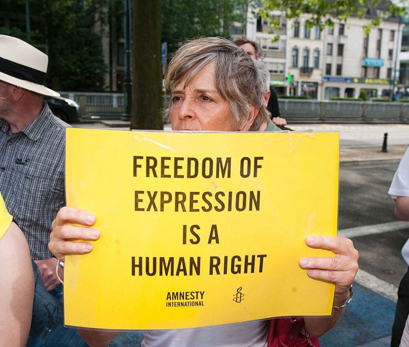 woman holds an Amnesty International sign that reads 