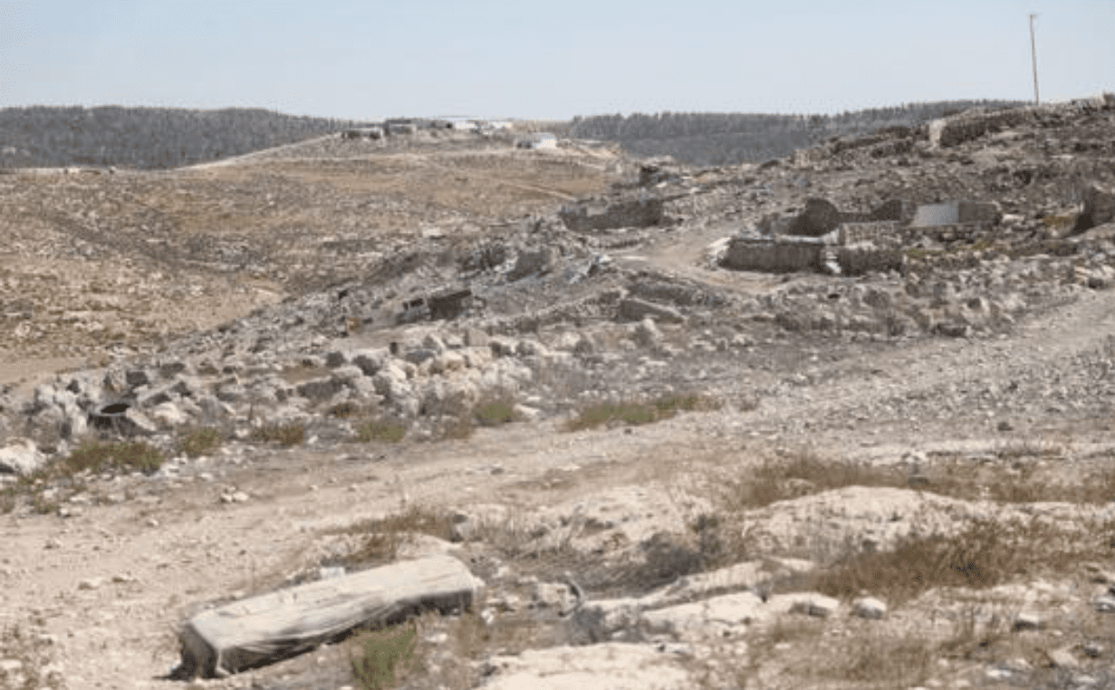 Ruins in Zanuta following the village’s destruction by settlers. Meitarim Farm is pictured in the background, on the overlooking hill.