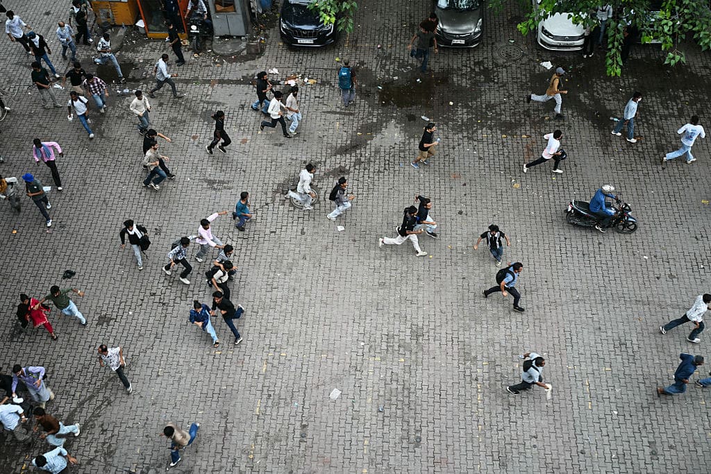 Seen from above, people run across open pavement, scattering in different directions.