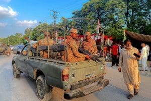 Soldiers sitting on a military truck holding guns.