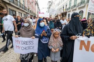 Female protesters wearing burkas march with placards.