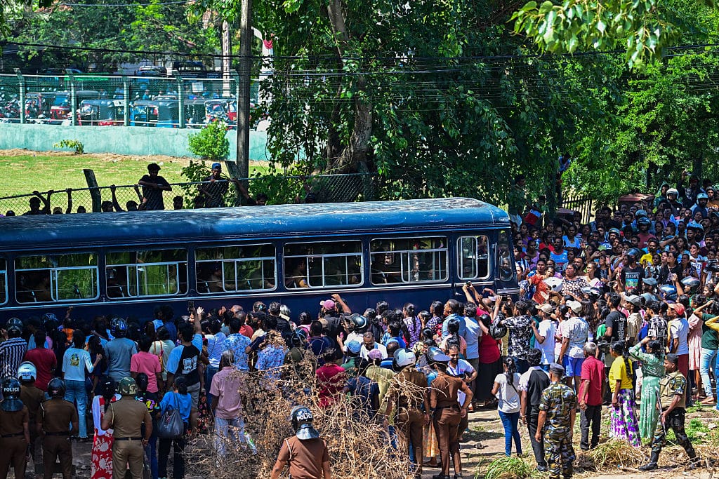 A blue bus with a crowd of people surrounding it.