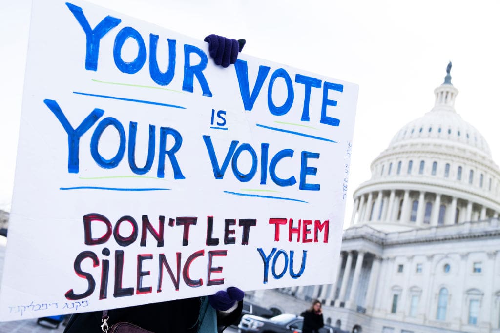 A demonstrator holds a sign that reads 