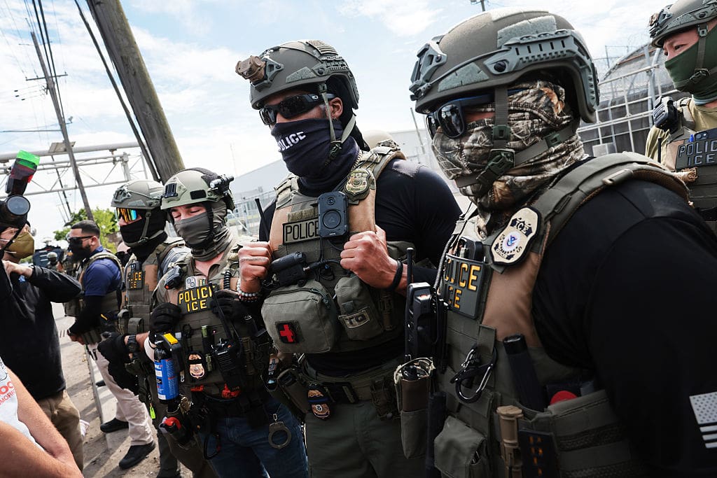 NEWARK, NEW JERSEY - MAY 26: ICE agents stand guard in front of protesters outside the federal immigration center at Delaney Hall in Newark