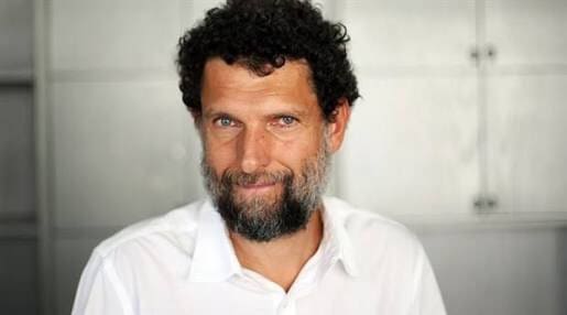 A middle aged man with curly brown hair, smiling.