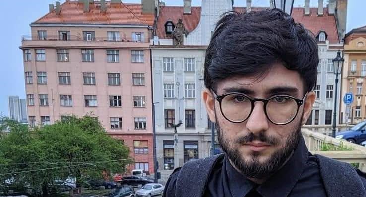 A young male with dark hair and glasses, looking at the camera.