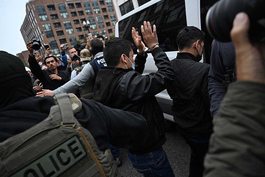 Federal Agents lead a detained immigrant to a waiting vehicle as activist protest outside the Intensive Supervision Appearance Program office on June 4, 2025 in Chicago, Illinois.