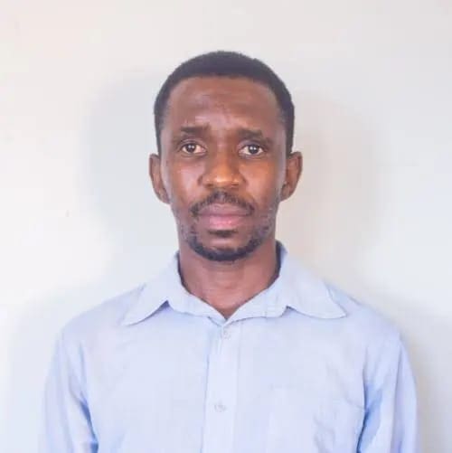 A fuzzy image of a man with a light blue button down shirt and a goatee looks at a camera against a white background, as if for a passport photo.