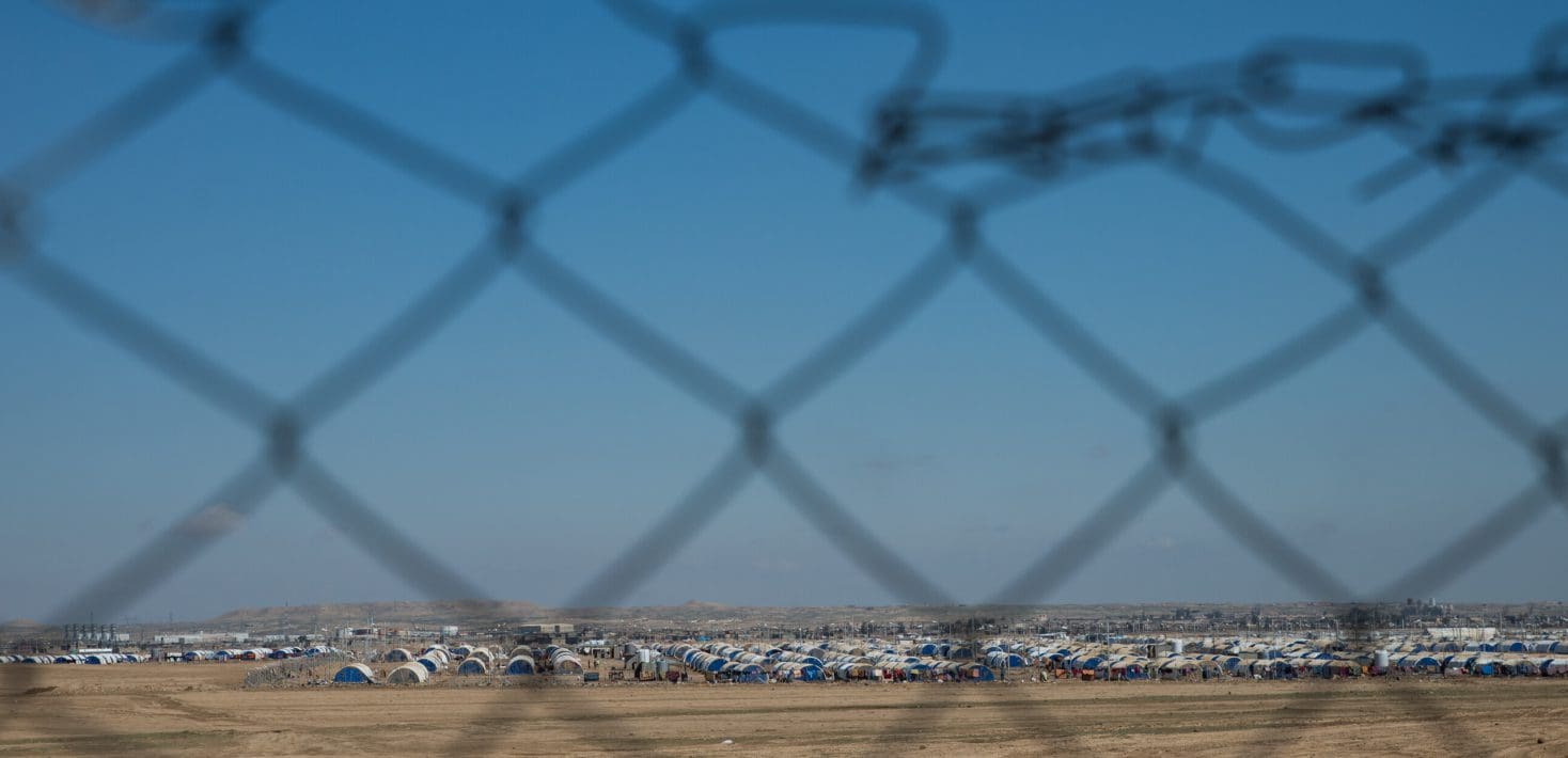 A refugee camp of tents seen through a chain link fence.
