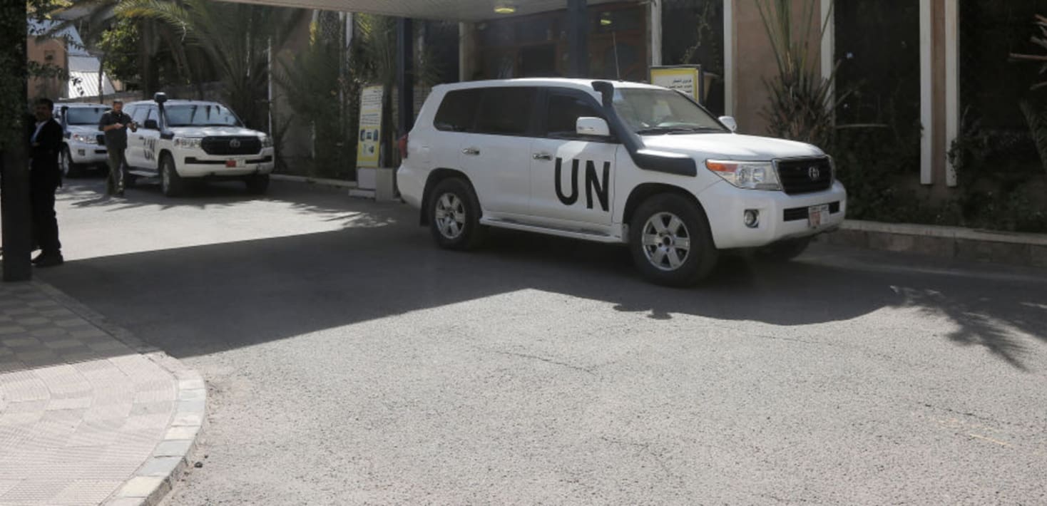 A row of white SUVs with the letters UN painted in black on the side.