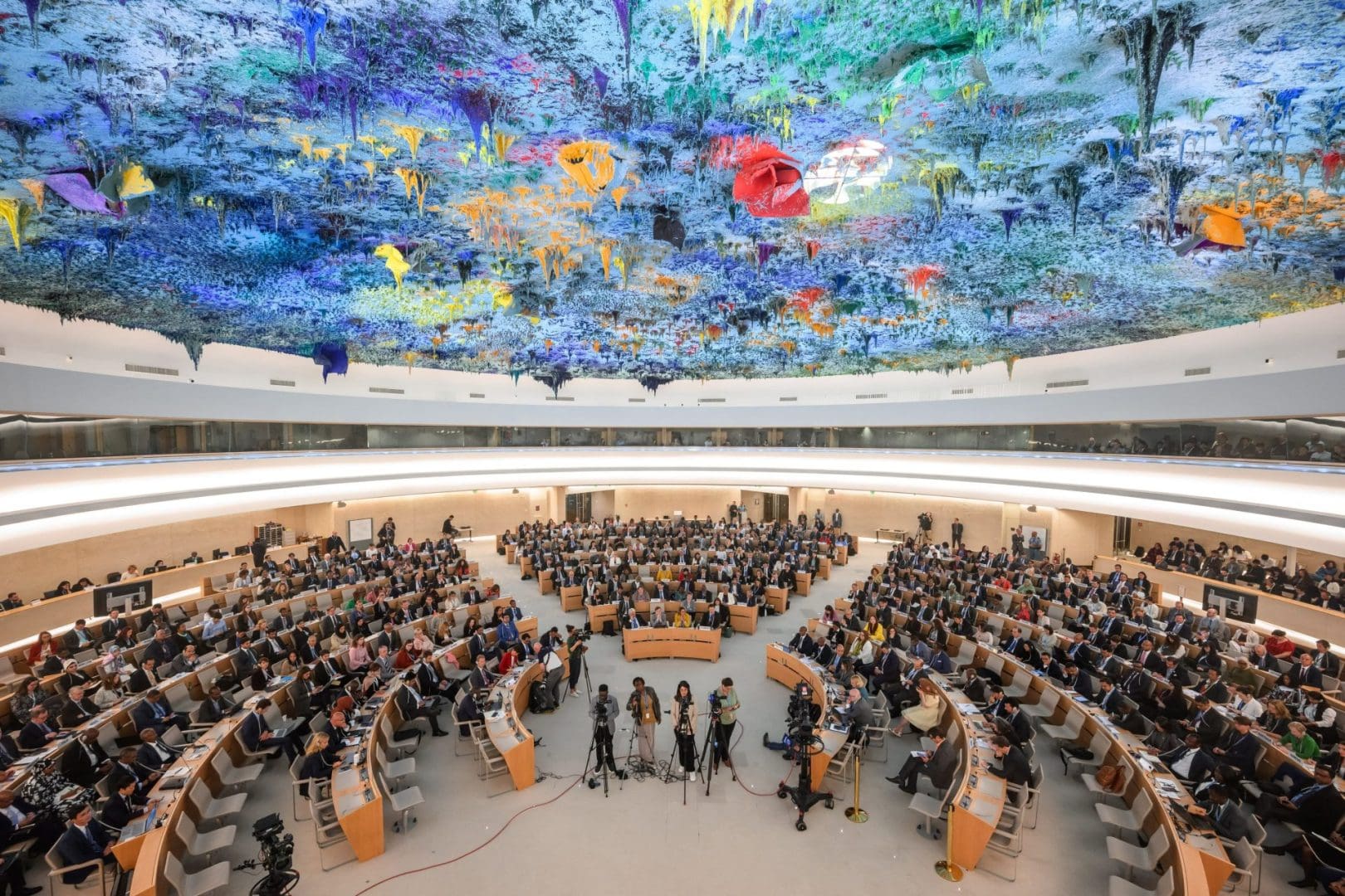 The UN Human Rights Council room, with a colorful ceiling and circular rows of desks.