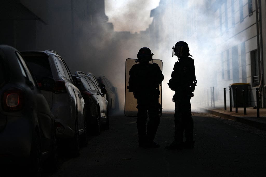 Riot police stand amid tear gas smoke